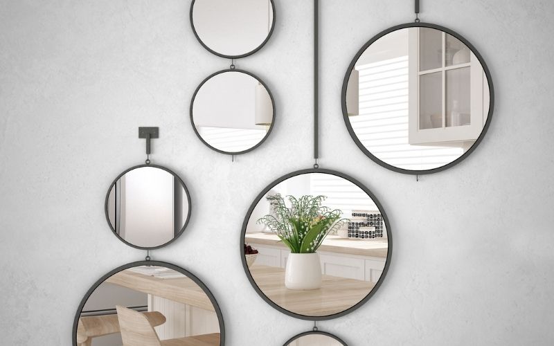 Photo of several round mirrors hanging on a white wall that can scare the birds away to avoid pooping on the porch