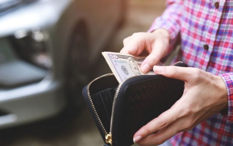 Image of two hands holding a wallet and some $50  bills